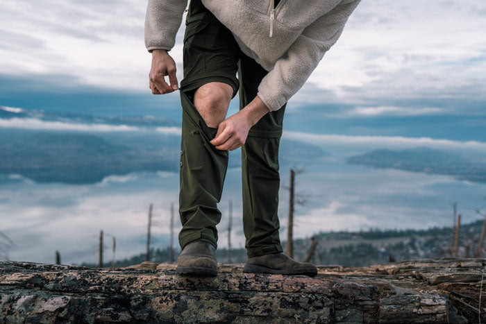 Men's convertible hiking pants with zip-off feature from Moosehill HikerFlex series being used for mountain trekking in changing temperatures.
